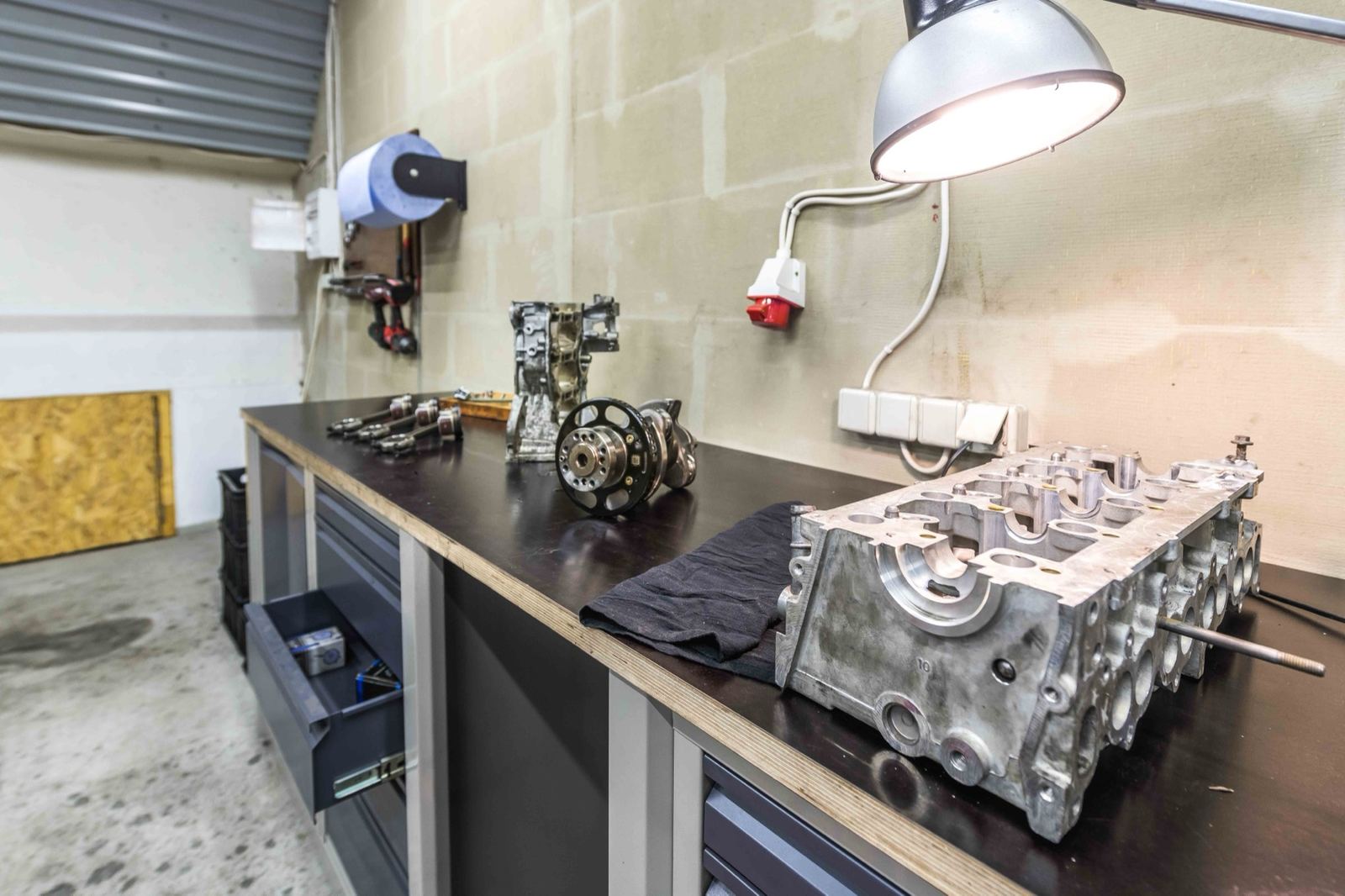 Zylinderkopf, Kurbelwelle und Pleuel auf der Werkbank in der Werkstatt von Augus Motors